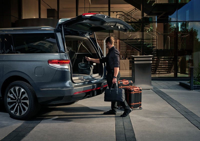 A valet is unloading luggage from the rear cargo area of a 2023 Lincoln Navigator SUV. | Gary Yeomans Lincoln Ocala in Ocala FL
