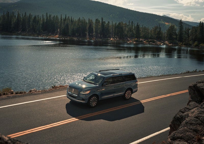 A 2023 Lincoln Navigator SUV is being driven on a lakeside road. | Gary Yeomans Lincoln Ocala in Ocala FL
