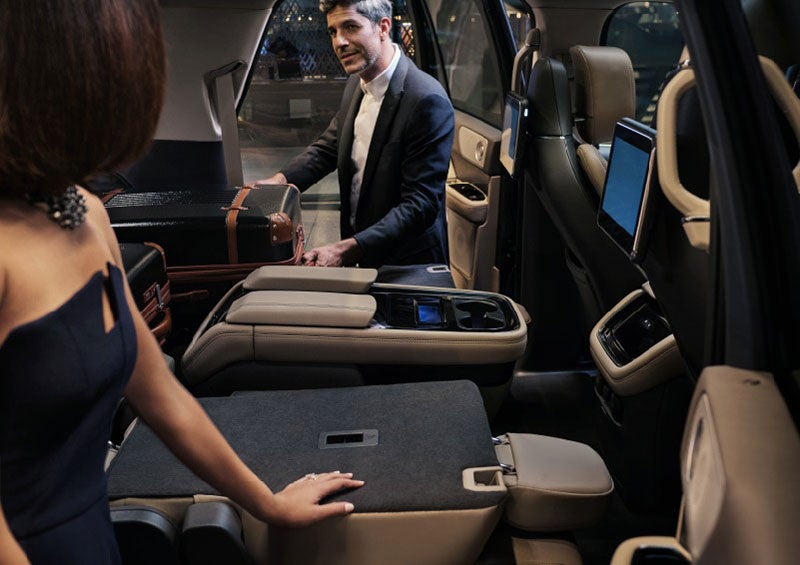 A man is pulling a suitcase out of the folded-flat second row of a 2023 Lincoln Navigator SUV. | Gary Yeomans Lincoln Ocala in Ocala FL