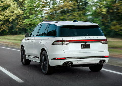 A white 2025 Lincoln Aviator® SUV is being driven away down a road lined with colorful trees. | Gary Yeomans Lincoln Ocala in Ocala FL