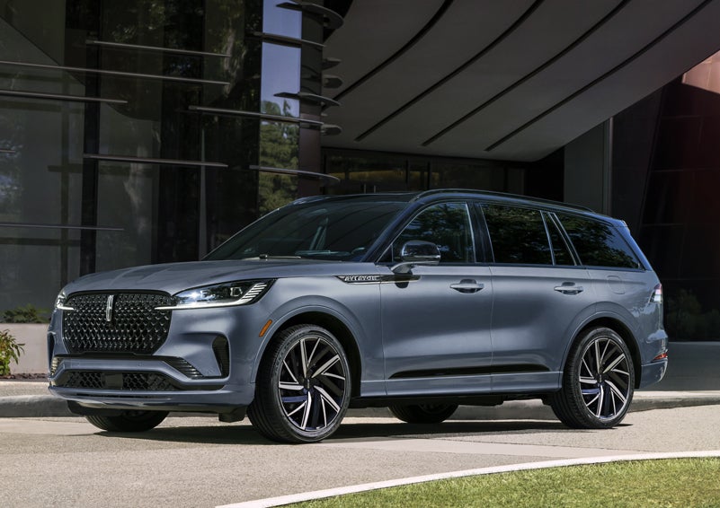 A gray 2025 Lincoln Aviator® SUV is parked outside a modern building showcasing the driver’s side of the vehicle. | Gary Yeomans Lincoln Ocala in Ocala FL