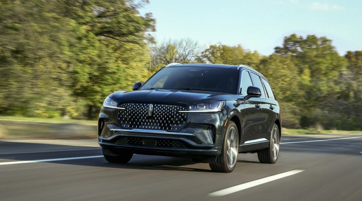A 2026 Lincoln Black Label™ Aviator® SUV is being driven down a road lined with trees. | Gary Yeomans Lincoln Ocala in Ocala FL