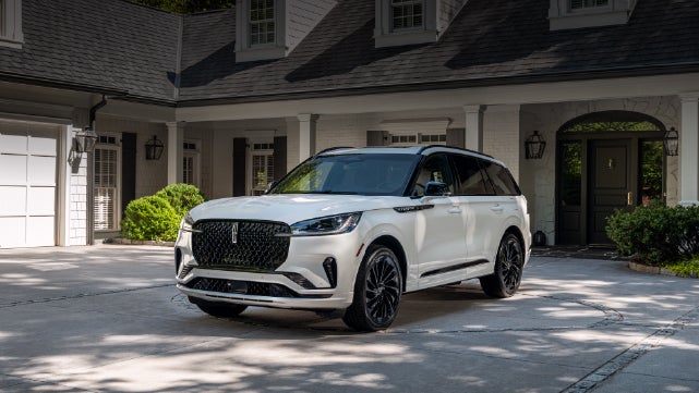 A white 2026 Lincoln Aviator® SUV is parked in the driveway of a luxury home. | Gary Yeomans Lincoln Ocala in Ocala FL