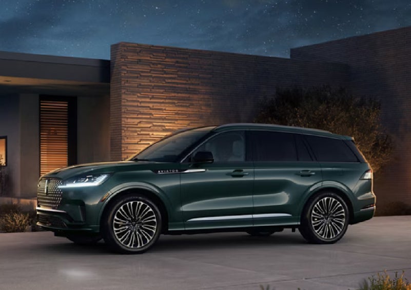 A green 2027 Lincoln Aviator® SUV is parked outside a contemporary home. | Gary Yeomans Lincoln Ocala in Ocala FL