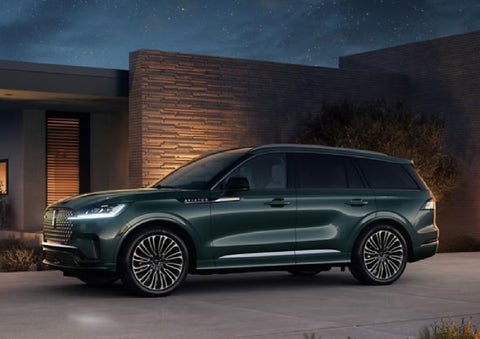 A green 2027 Lincoln Aviator® SUV is parked outside a contemporary home. | Gary Yeomans Lincoln Ocala in Ocala FL