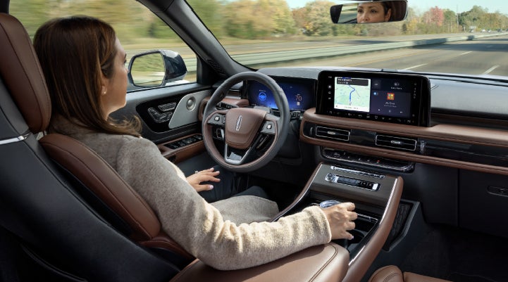 A 2027 Lincoln Aviator® SUV is being driven hands-free on a highway lined with trees. | Gary Yeomans Lincoln Ocala in Ocala FL