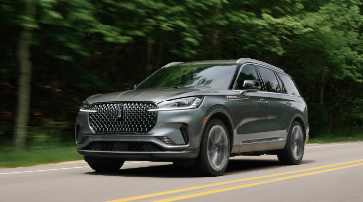 A 2027 Lincoln Aviator® SUV is being driven down a road lined with trees. | Gary Yeomans Lincoln Ocala in Ocala FL
