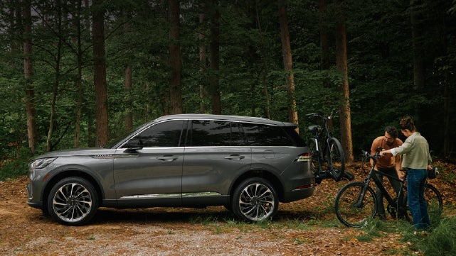 A father and son load e-bikes on a bike rack attached to a 2027 Lincoln Aviator® SUV. | Gary Yeomans Lincoln Ocala in Ocala FL