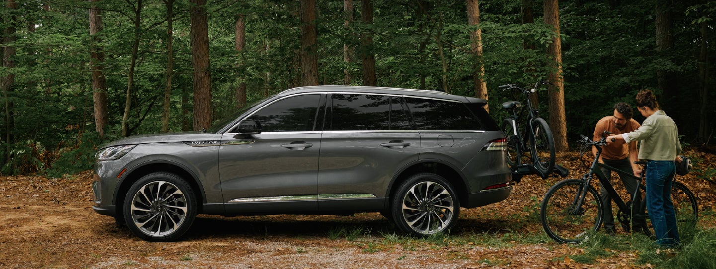A father and son load e-bikes on a bike rack attached to a 2027 Lincoln Aviator® SUV. | Gary Yeomans Lincoln Ocala in Ocala FL